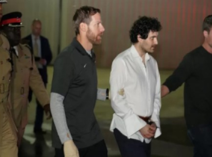 Sam Bankman-Fried in white shirt being accompanied by US and Bahamas law enforcement authorities as he is extradited to the United States