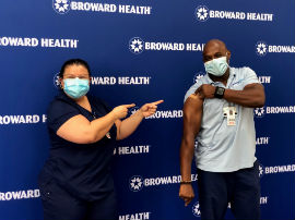 James McCrae, RN and nurse manager of the critical care unit at Broward Health North, and Roseitta Da Silva, RN, are all smiles while posing for a photo after McCrae received his Pfizer COVID-19 vaccine.