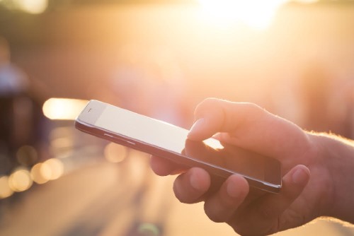 Man using his Mobile Phone outdoor, close up