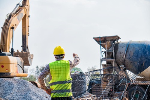 The construction site where concrete is poured with cement mixing workers. And large machinery