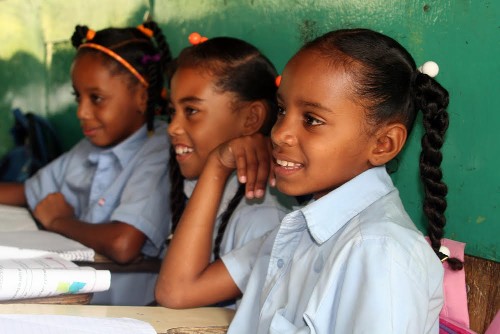 Three young schoolgirls sitting next together in the classroom