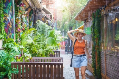 Young woman smiles and laughs under the rain. Girl enjoying warm summer tropical rain