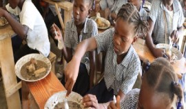 Students eat lunch at their school in Belle Onde village, in central Haiti. (World Food Programme photo)