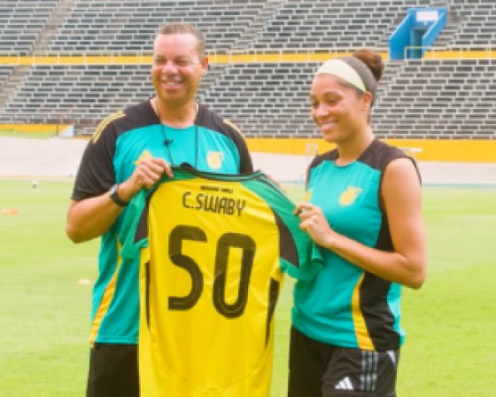 Reggae Girls coach Hubert Busby hands over a symbolic jersey to Chantelle Swaby, who is set to get her 50th cap for Jamaica. Photo: JFF