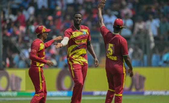 Jason Holder (centre) is congratulated by teammates Gudakesh Motie (left) and Matthew Forde after picking up one of his four wickets against Nepal.