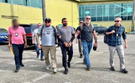 U.S. Marshals and agents from TTPS and the U.S. Diplomatic Security Service escort Farzan Mohammed at the Piarco airport for his extradition to the United States for crimes against children