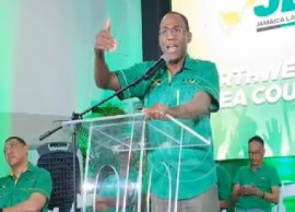 Outgoing Finance Minister, Dr. Nigel Clarke, addressing a JLP meeting on Monday night. Prime Minister Andrew Holness (left) listens to the address (CMC Photo)