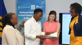 Minister of the Environment and National Beautification, Adrian Forde, and Executive Director of Common Seas, Dr. Charlotte Davies looking over the National Action Plan to End Plastics Pollution (BGIS Photo)