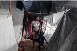 A pregnant woman with a child walks between tents in Haiti (UN Photo)