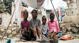 A mother sits with her children in an IDP site in Léogâne, on the outskirts of the Haitian capital, Port-au-Prince (UNICEF/Maxime Le Lijour)