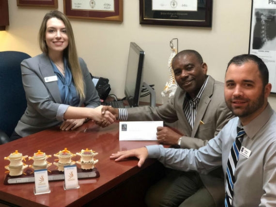 Dr. Laura Hochstein (left) of County Line Chiropractic Medica and Rehab Center presents sponsorship check to Eddy Edwards, (center) CEO of Jamaican Jerk Festival USA, Inc., while Dr. Angel Ares looks on.