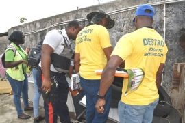 Members from the Manchester vector control unit conduct a search and destroy operation on the grounds of the Mandeville Police Station recently.
