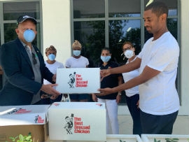 Jamaica’s Consul General to Florida Olive Mair at left – presents care package to Jamaican Hotel Worker Donovan Irwin,one of Jamaica’s hotel workers, who were displaced as a result of the Covid-19 Pandemic. Looking on are other Jamaican hotel workers.
