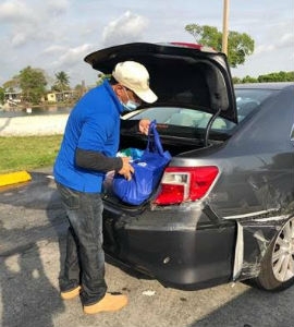 Commissioner Martinez placing bagged food in residents’ cars