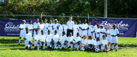 Students participating in the Real Madrid Foundation soccer clinics in Negril gather for a photo with coach Carlos after receiving their certificate of participation