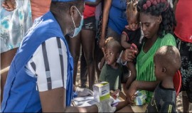 A UN staff member provides medical care to a displaced woman and children. (Photo courtesy UNOCHA/Giles Clarke)